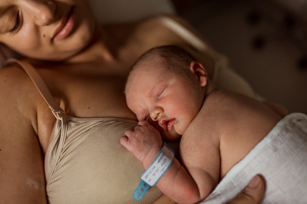 noworodek z opaską w szpitalu śpi przytulony do mamy