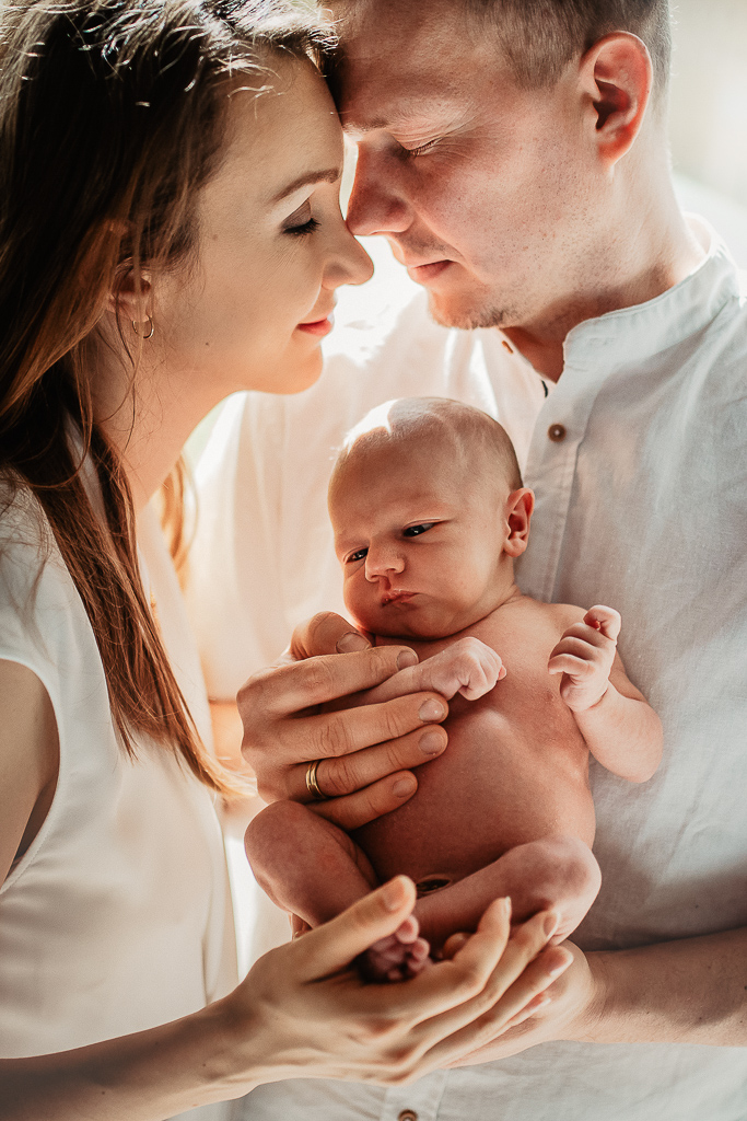 noworodek w ramionach rodziców naturalne światło wpada do domu