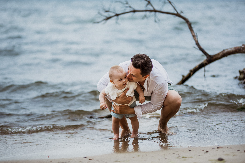 tata bawi się z córeczką w wodzie na plaży