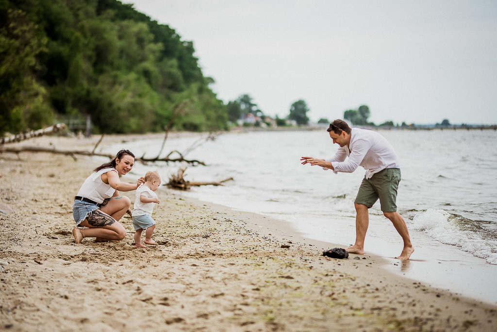 rodzice bawią się z dzieckiem na plaży w Pucku