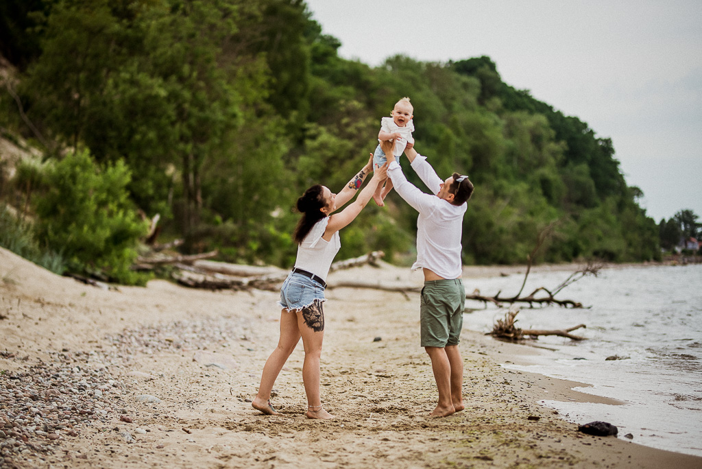 rodzice bawią się z dzieckiem na plaży w Rewie