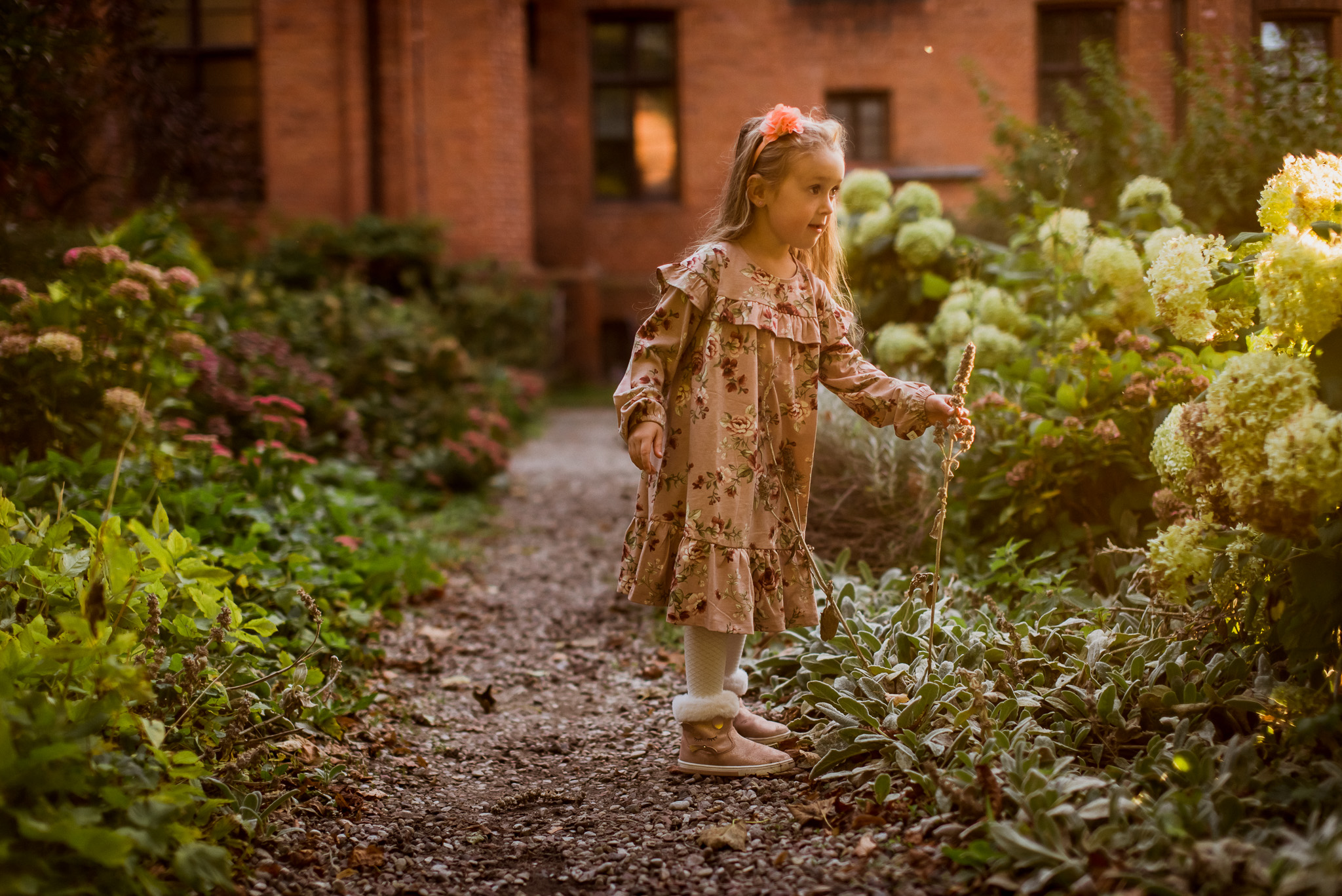 dzieci biegają po ogrodzie pełnym kwiatów