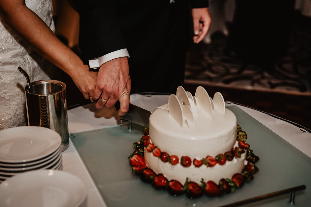 tort weselny para młoda kroi z owocami 