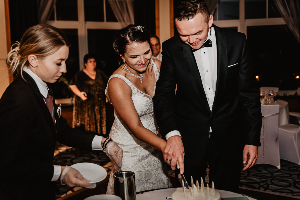 tort weselny para młoda kroi z owocami 