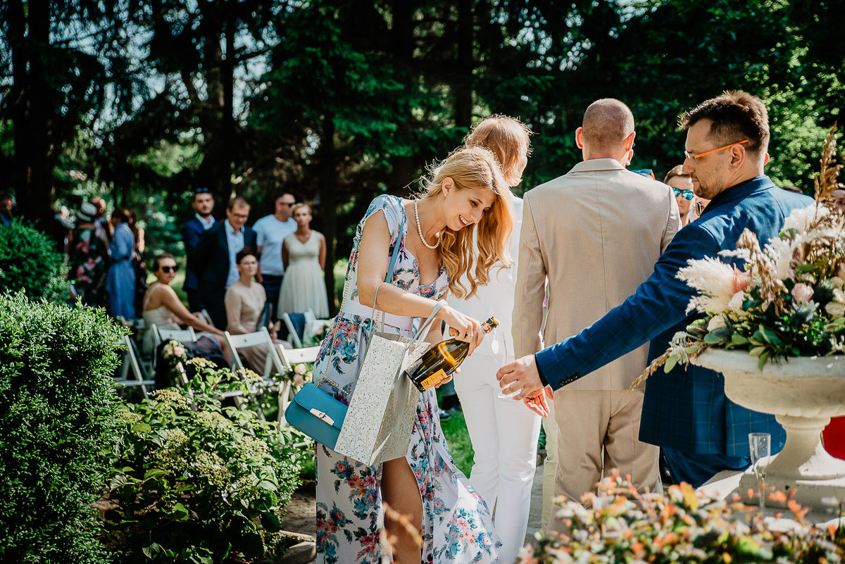 świadkowa otwiera prosecco na ślub w plenerze