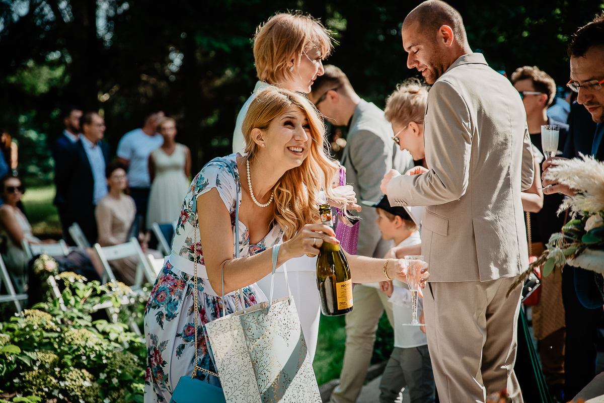 świadkowa ma sukienkę w kwiaty i otwiera prosecco na ślub w plenerze