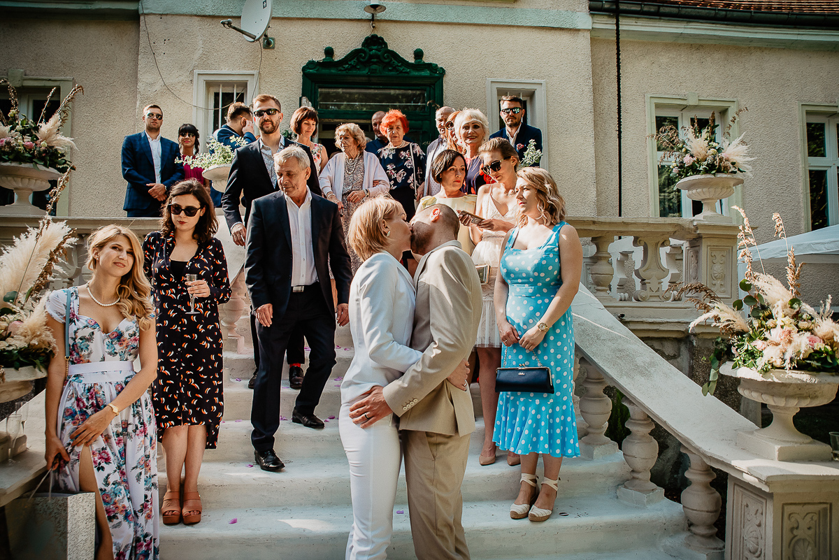 para młoda całuje się przy gościach przed starą kamienicą