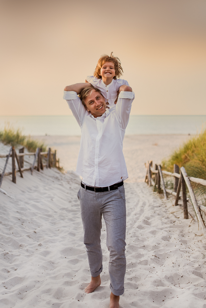 tata nosi syna na plecach na plaży