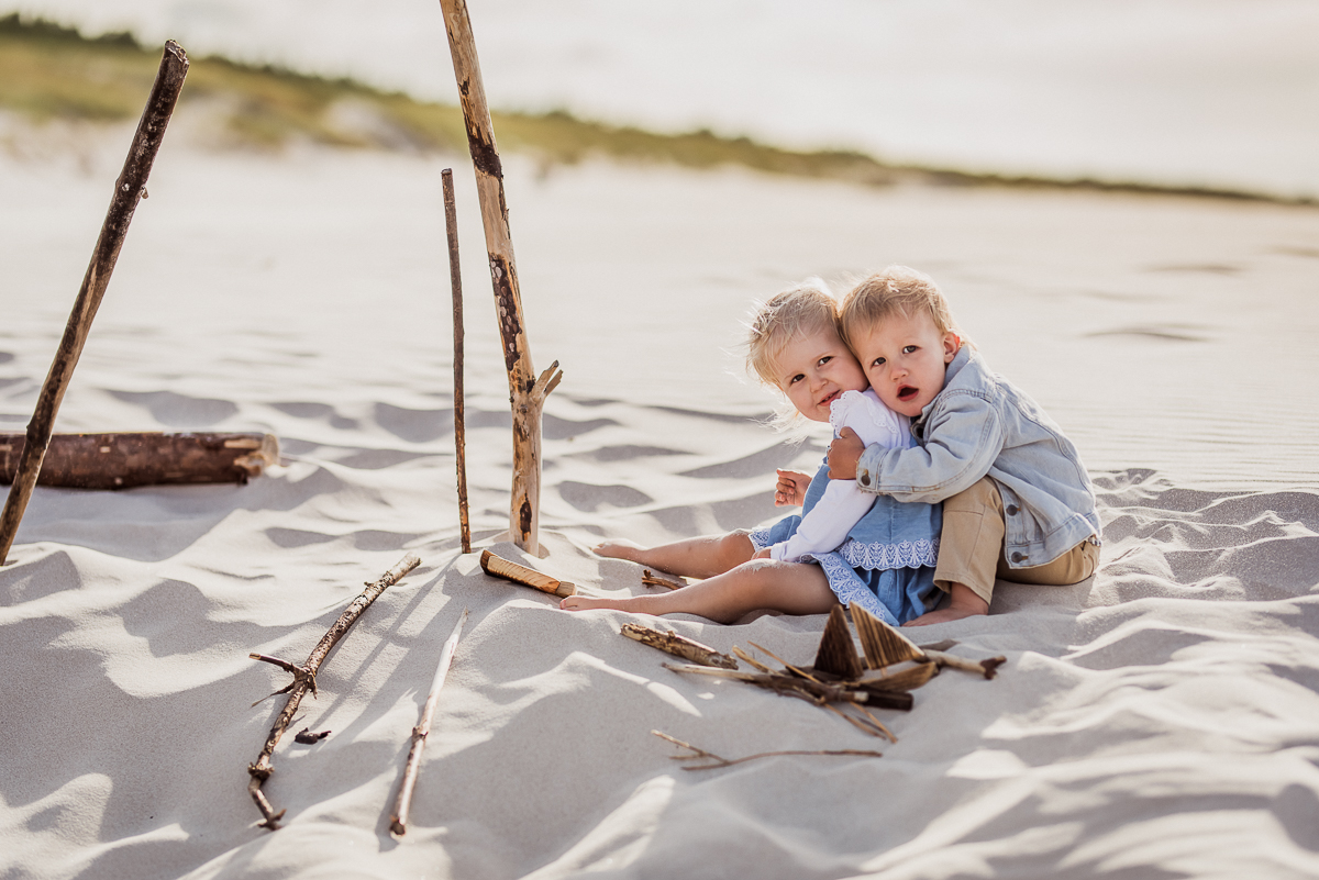 dzieci 2 letnie przytulają się na plaży siedząc na piasku w Jastrzębiej Górze