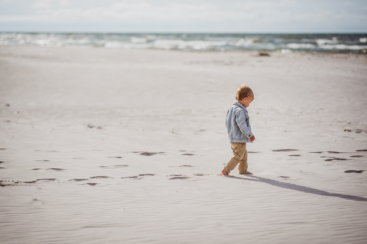 chłopiec idzie plażą w stronę morza