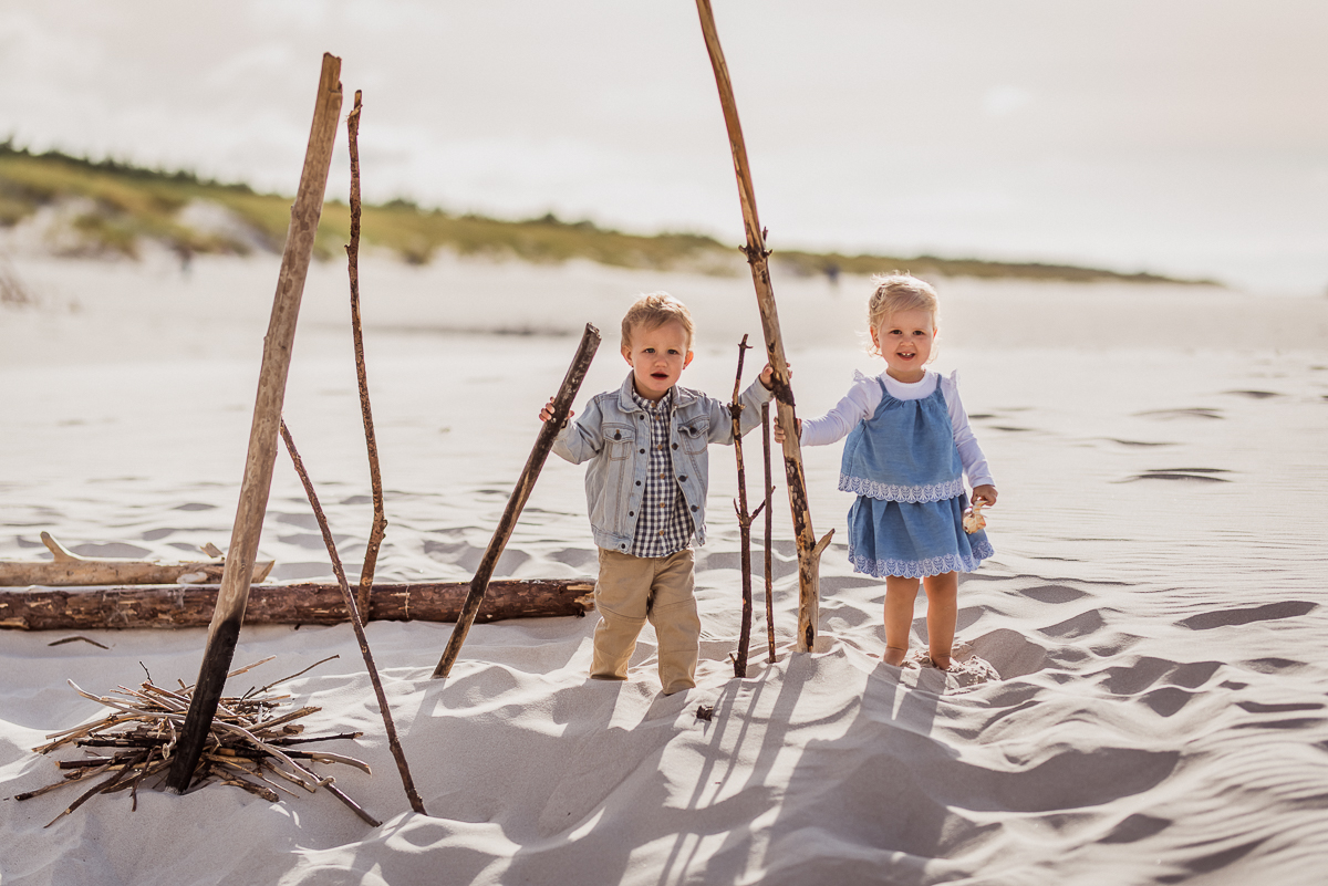 chłopiec i dziewczynka w niebieskich ubraniach na plaży bawią się 