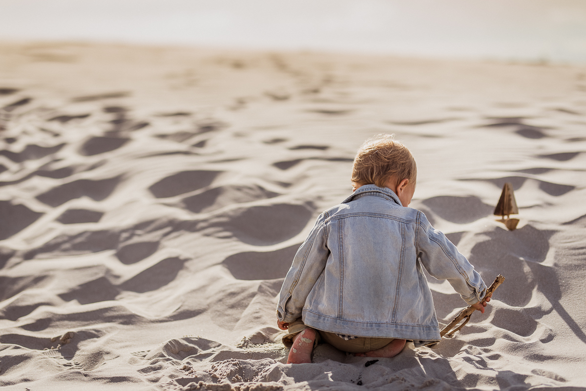 chłopec 2 letni bawi się piaskiem na plaży