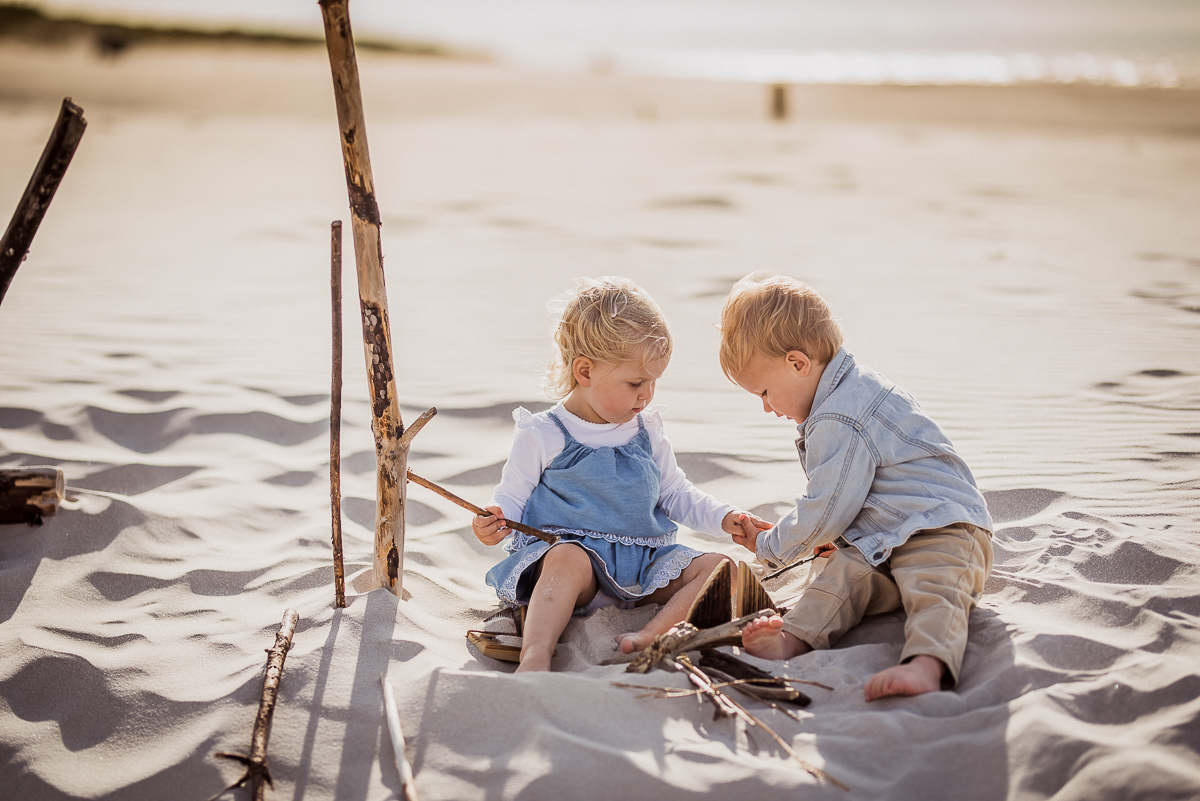 chłopiec dotyka rączki koleżanki zabawa na plaży w piasku